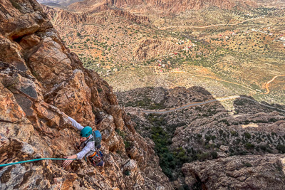 Person rock climbing high above a village in the Anti Atlas Mountains
